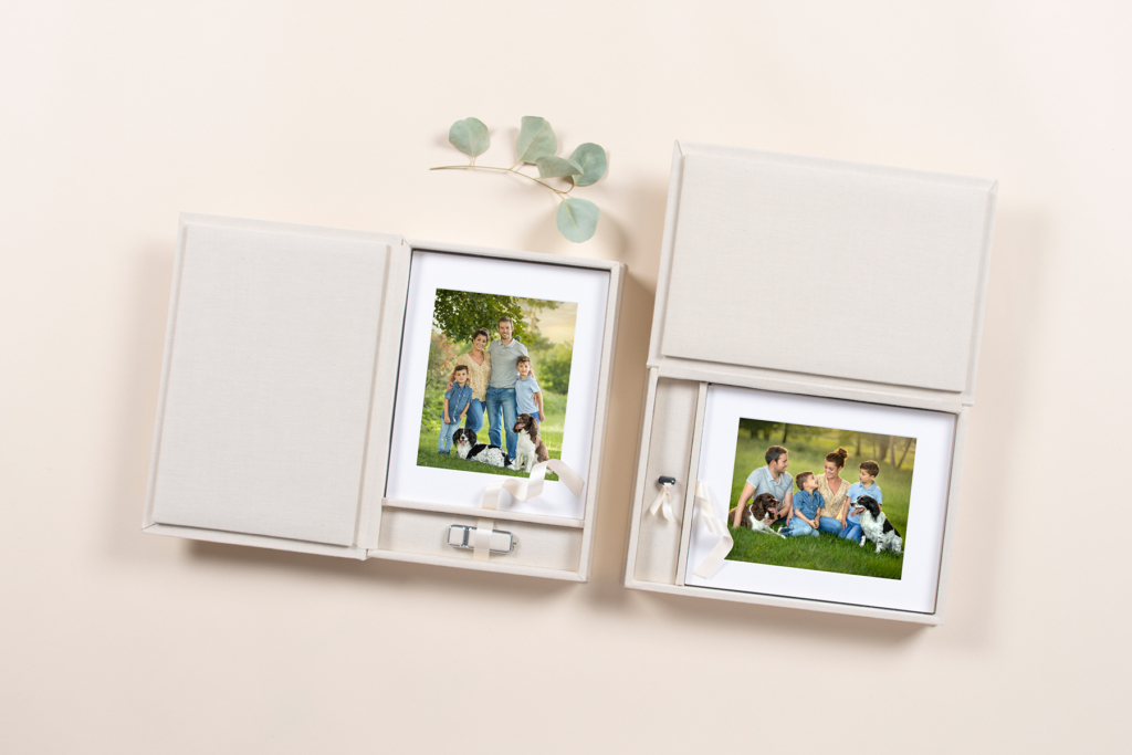 creame folio boxes with family portrait images sitting on a cream background with a sprig of eucalyptus