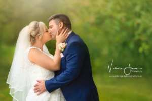 bride & groom kissing with beautiful out of focus green background