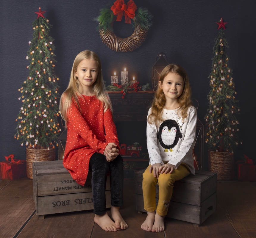 Girls sitting in front of beutiful Christmas fireplace scene for Christmas mini session 2021